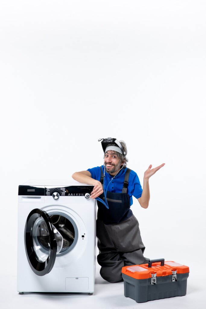 front-view-cheerful-repairman-with-stethoscope-sitting-near-washing-machine-raising-his-hand-white-space